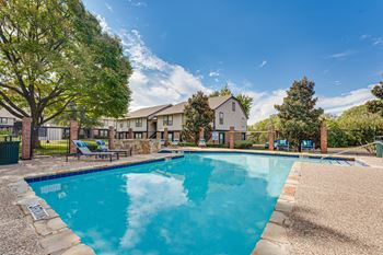 Swimming pool with lounge chairs and brick fence